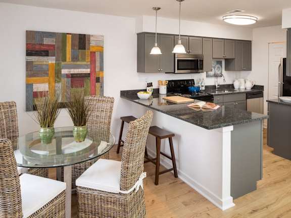Apartment kitchen with stainless steel, granite countertops, and dark cabinetry