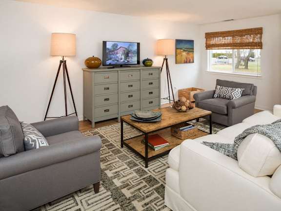 Furnished living room with a sofa, lounge chairs, coffee table, and high ceiling at Yardley Crossing
