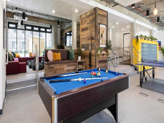 a pool table in a lobby of a building with a couch