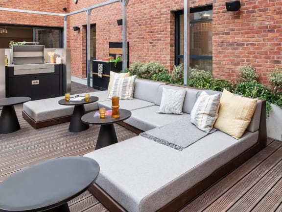 a patio with couches and tables and a brick wall