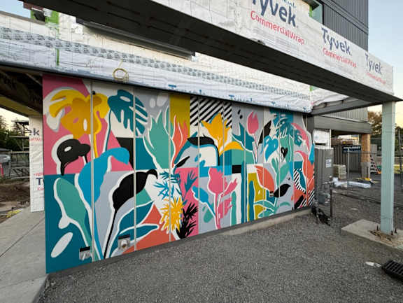 A mural of flowers painted on a wall under a bridge.