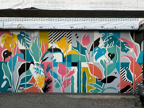 A wall with a colorful mural of abstract shapes and flowers.