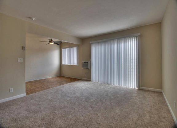 an empty living room with a window and a ceiling fan