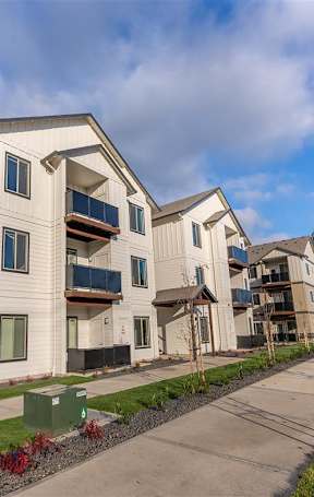 The exterior of an apartment building with patios and balconies at Woodburn Place Apartment Homes, Woodburn, OR, 97071
