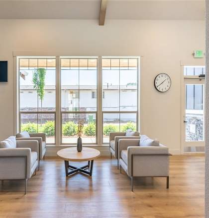 A waiting room with grey couches and a wooden floor at St Helens Place Apartment Homes, St Helens, OR, 97051