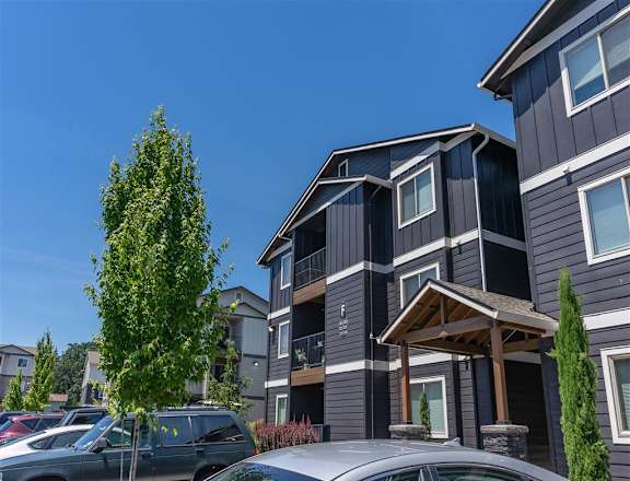 A modern two-story building with a parking lot in front. at St Helens Place Apartment Homes, St Helens, 97051