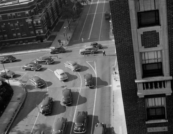 a black and white photo of a city intersection with cars