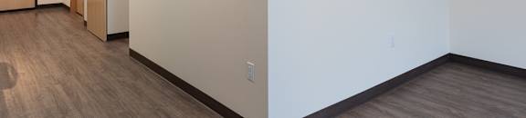 A room with a white wall and a brown floor.