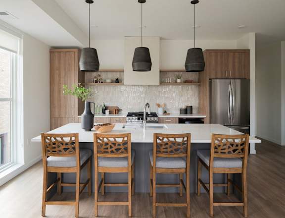 A kitchen with a white countertop and wooden chairs.