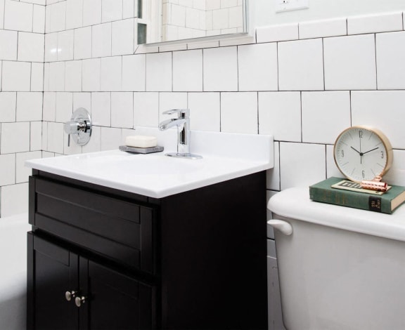 a bathroom with a sink and a clock on the toilet