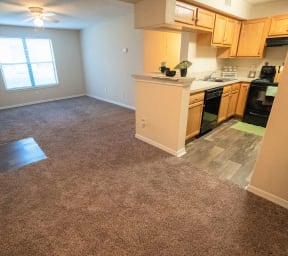 Northlake Apartments Jacksonville, Florida open-concept floor plan with carpeted living and dining areas, vinyl flooring in foyer and kitchen, wood kitchen cabinets, and ceiling fan in living room
