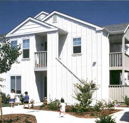 A white two story house with children playing in front.