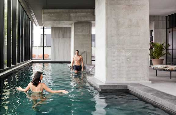 A man and a woman are enjoying a swim in a modern indoor pool.