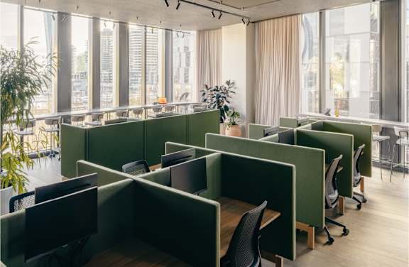 A modern office with green cubicles and plants.