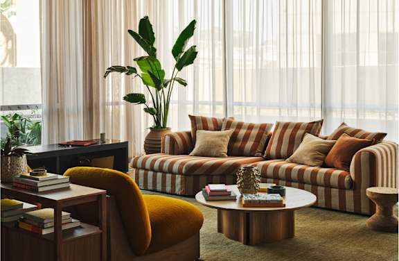 A living room with a striped sofa and a yellow chair.