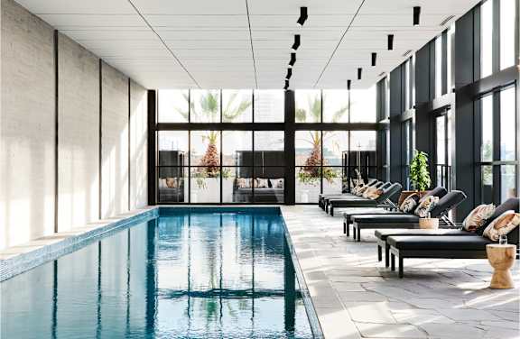 A large indoor swimming pool with lounge chairs and a view of the outdoors.