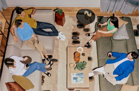 A group of people are sitting and lying on couches in a living room.