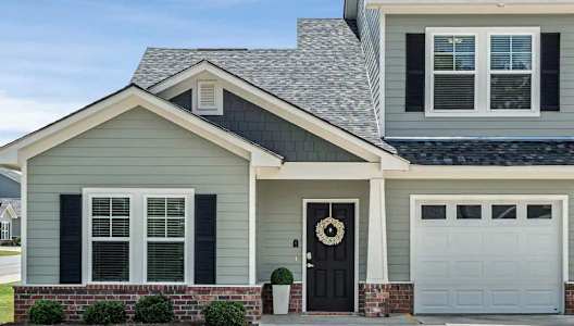 a gray house with a black door and a white garage door