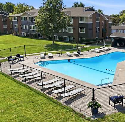 A swimming pool surrounded by sun loungers and a fence.