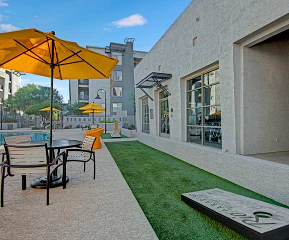 The pool area with chairs, tables, umbrellas, and games at Rio Paradiso Apartment Homes. 
