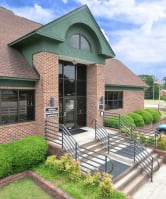 the front of a brick building with stairs and a parking lot