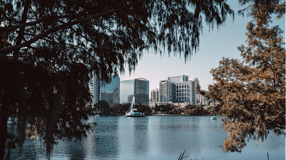 A cityscape with buildings and a body of water in the foreground.