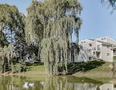 a house sits on the bank of a lake with trees