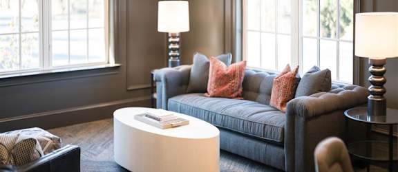 A seating area with a tufted sofa, throw pillows, and large windows.