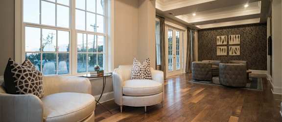A bright lounge with cozy armchairs, large windows, and hardwood floors.