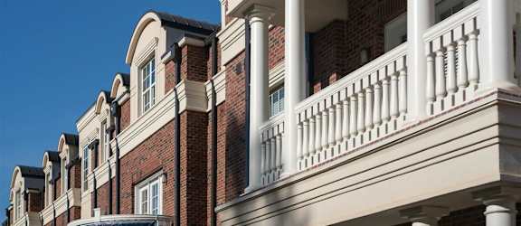 Classic brick apartment building at Tindall Park Apartments featuring elegant white columns and decorative balconies.