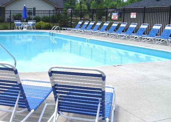 A pool with blue chairs around it.