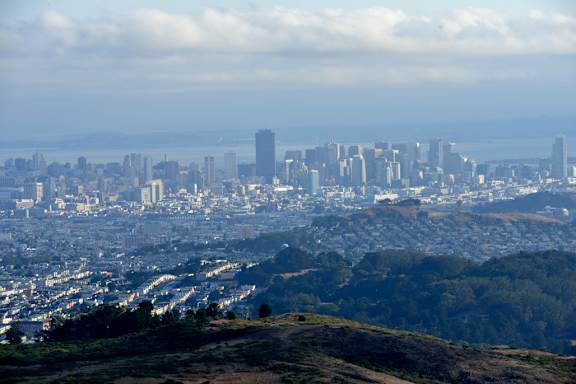 A cityscape with buildings and hills in the foreground.