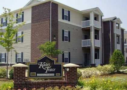 A brick building with a sign that says Kates Trace in front of it.