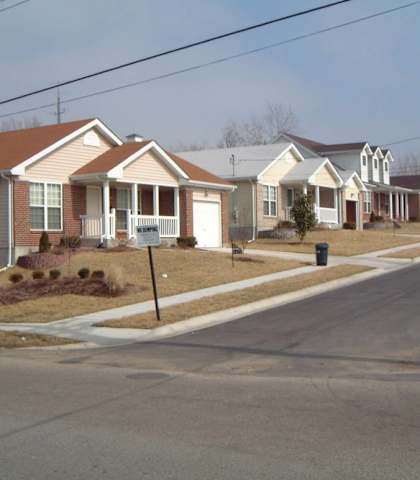 A street view of a residential area with houses and a car parked on the side.