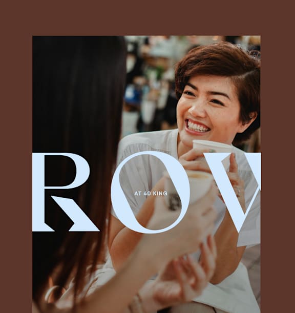 A woman is laughing while holding a cup of coffee.