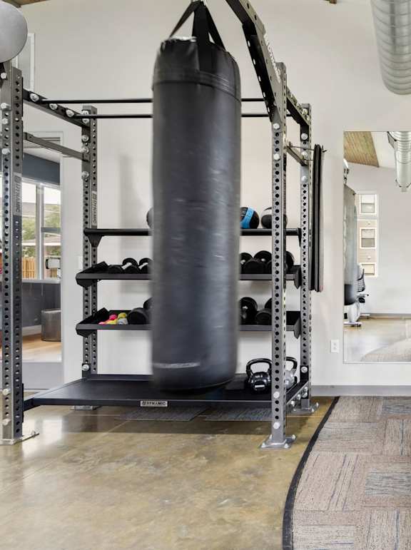 A gym with a punching bag, bench, and a television mounted on the wall.