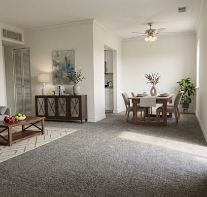 A living room with a grey sofa, a wooden coffee table, and a dining table with chairs.