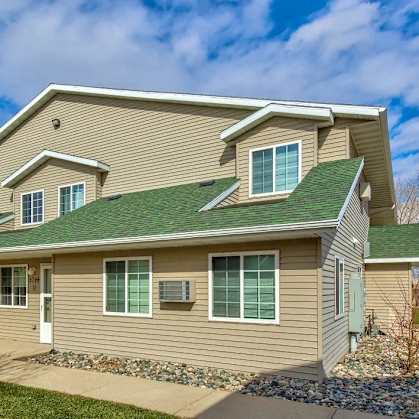 a house with a green roof and a sidewalk. Fargo, ND Foxtail Townhomes
