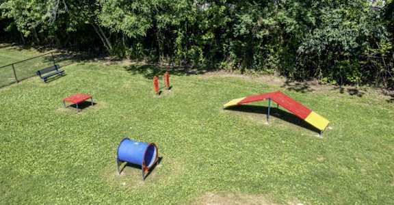 a grassy field with a playground and trees in the background at Station JTown, Louisville, KY, 40299