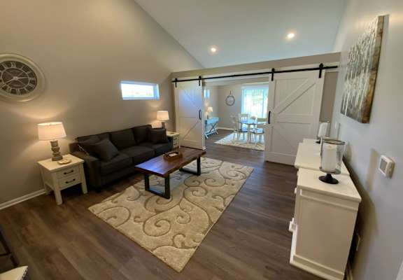 A living room with a brown couch and a rug.
