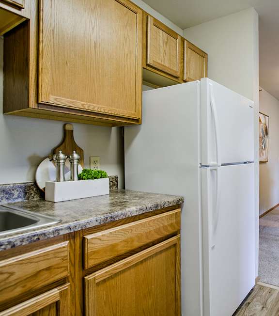 A kitchen with a white refrigerator and wooden cabinets.