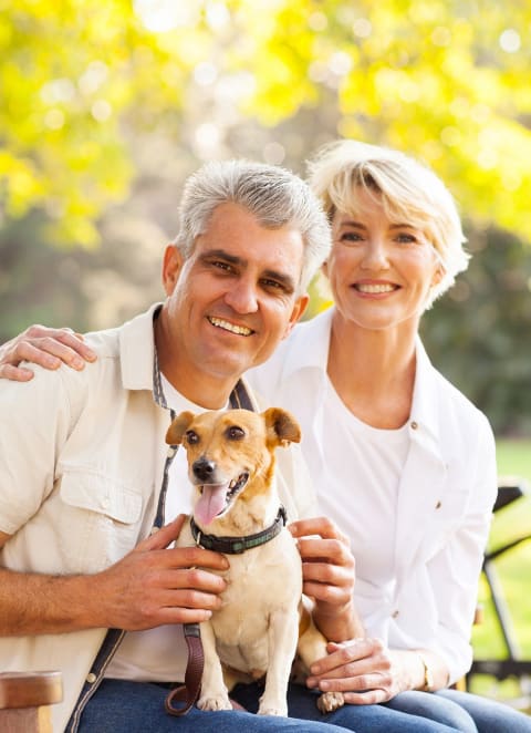 a man and woman sitting on a bench with a dogat The Portofino 55+ Apartments, Pasadena