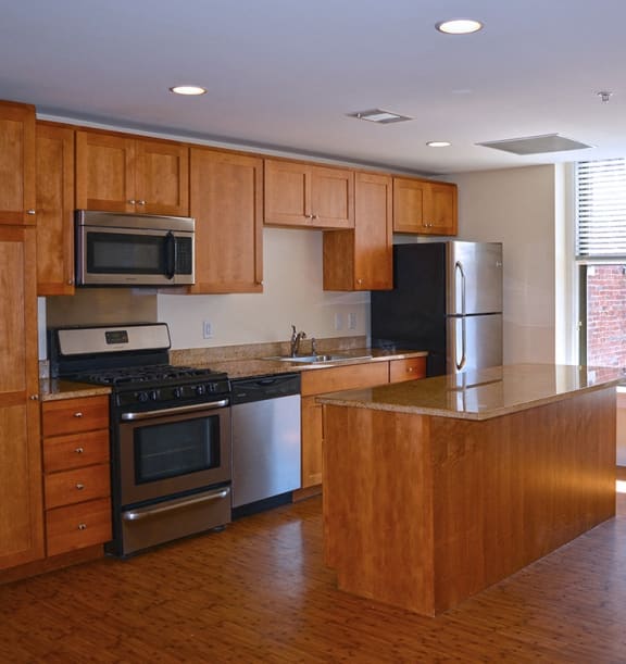an empty kitchen with wooden cabinets and stainless steel appliances at The Laurel Apartments, Saint Louis, 63101