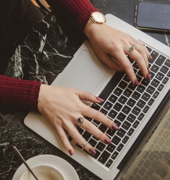 A person's hands typing on a laptop keyboard.