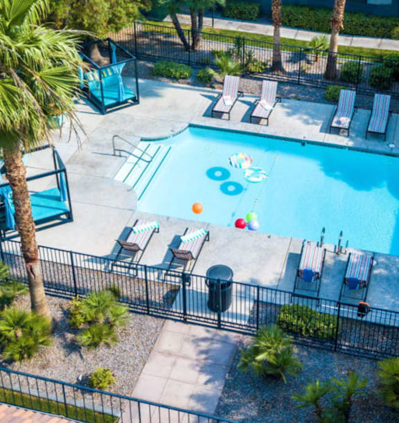 A pool surrounded by palm trees and lounge chairs.