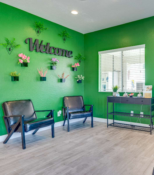 a dentist office with green walls and chairs and a welcome sign