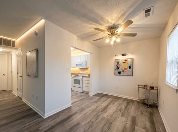 A room with a ceiling fan and a painting on the wall.