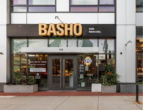 The front of a restaurant named Basho with a sign that says Sushi Grill.