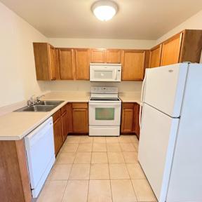 A kitchen with white appliances and wooden cabinets.