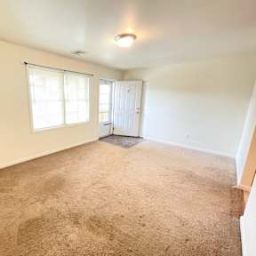 A room with carpeted floor and a door leading to another room.